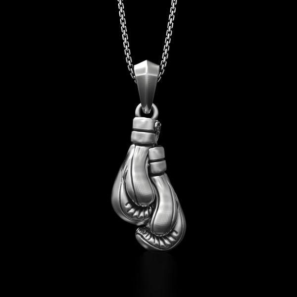 Silver boxing gloves pendant on a chain against a black background