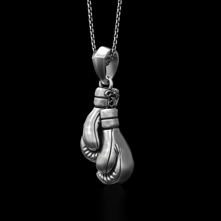 Silver boxing gloves chain necklace against a black background