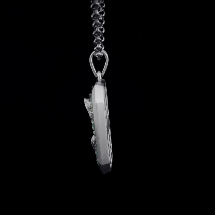 Silver pendant on a chain against a black background