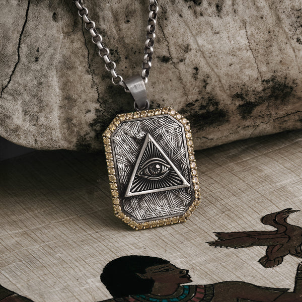Necklace with pyramid and eye pendant on a textured surface