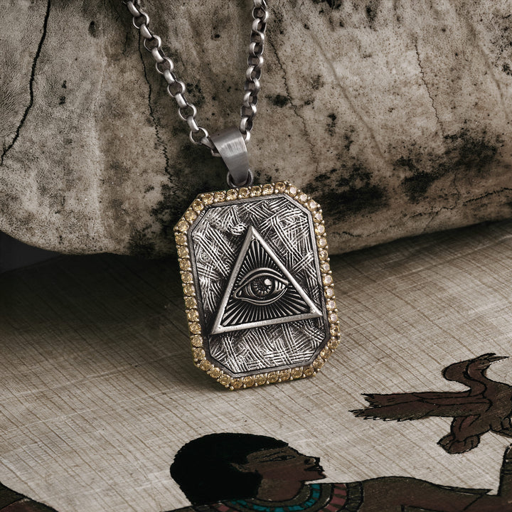 Necklace with pyramid and eye pendant on a textured surface