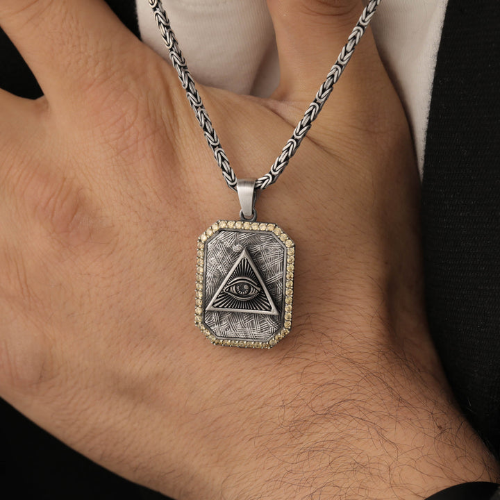 Silver eye symbol necklace with a pendant featuring an eye design on a person's hand.