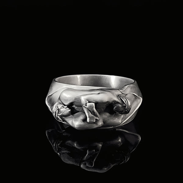 Silver ring with a detailed lovers embrace design on a black background