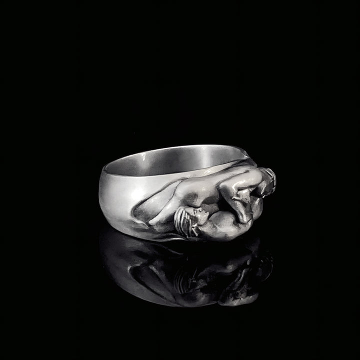 Silver ring with a detailed gay design on a black background