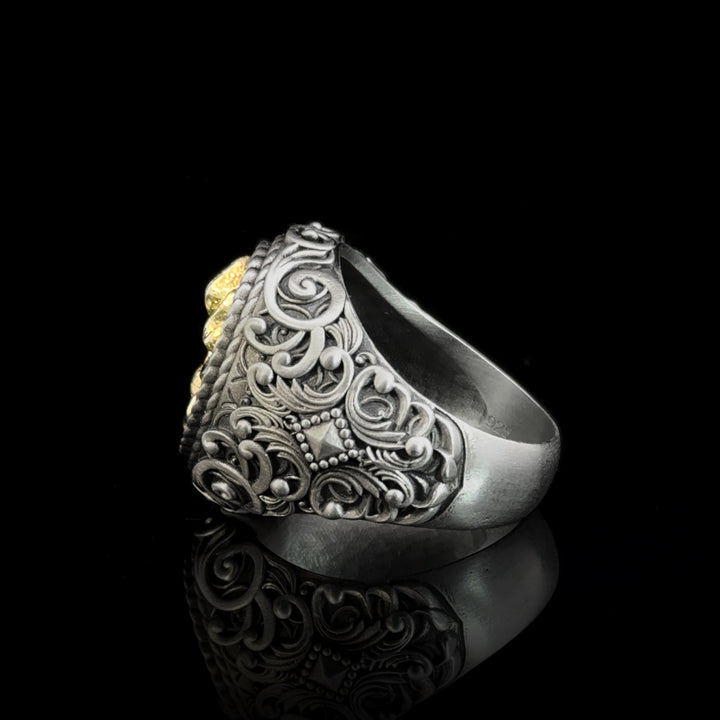 Silver skull ring with intricate vintage designs on a black background