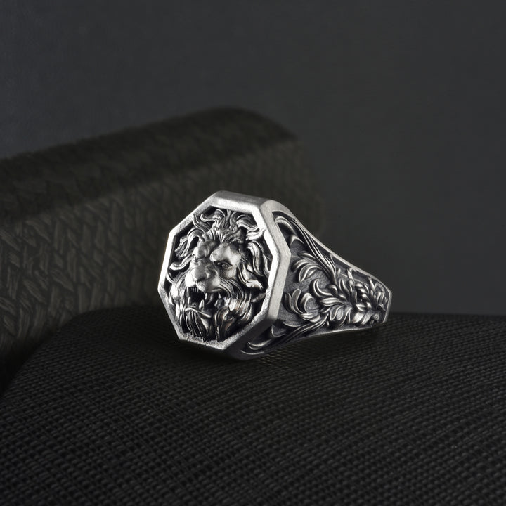 Vintage lion head ring on a textured black surface with a dark background