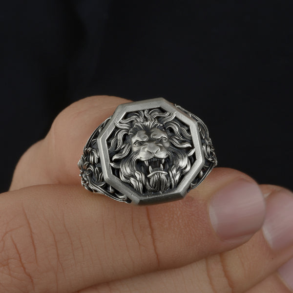 Silver lion head ring on a finger against a dark background