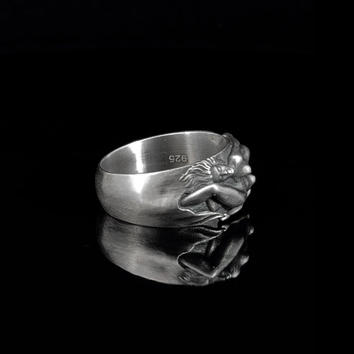 Silver ring with women in embrace design on a black background