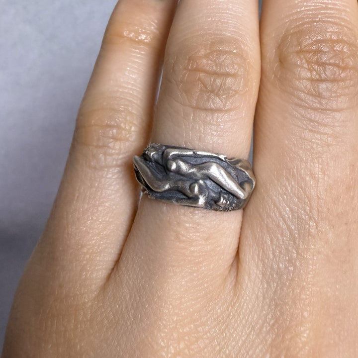 Silver women lovers band ring on a finger with a plain background