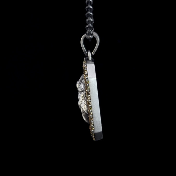 Close-up of a silver necklace with a pendant on a black background