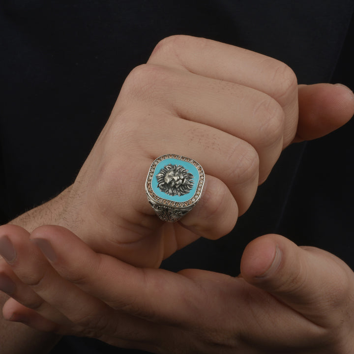 Hand wearing a decorative ring with a blue gemstone and bold animal head on a black background