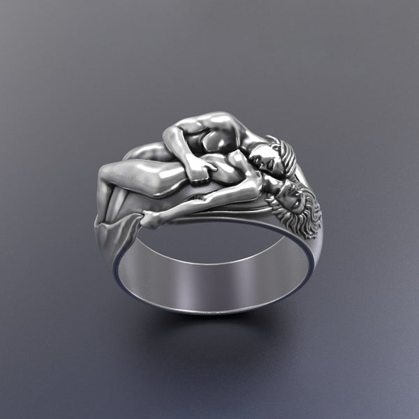 Silver ring with intricate romantic couple design on a dark gray background