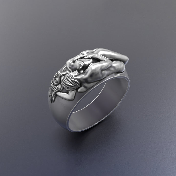 Silver ring with a hugging lovers design on a dark gray background