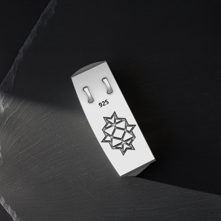 Silver pendant with '925' stamp on a dark stone surface