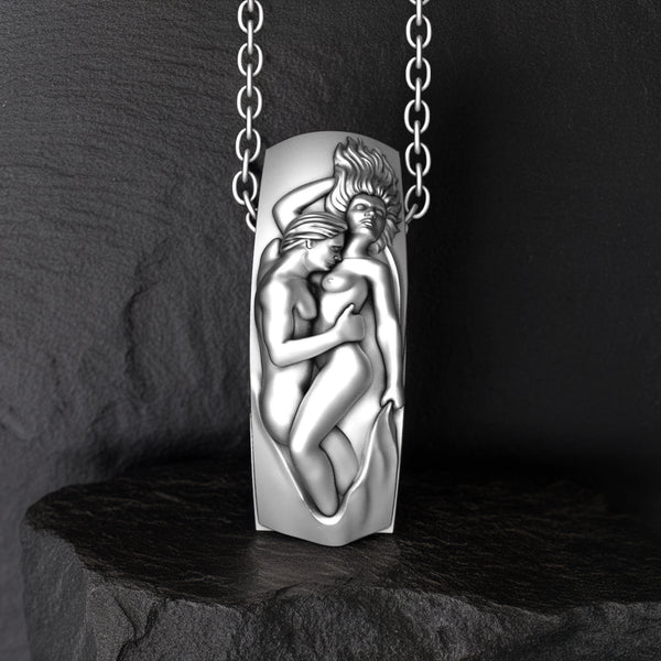 Silver pendant with a design of two lovers embracing on a dark stone surface.