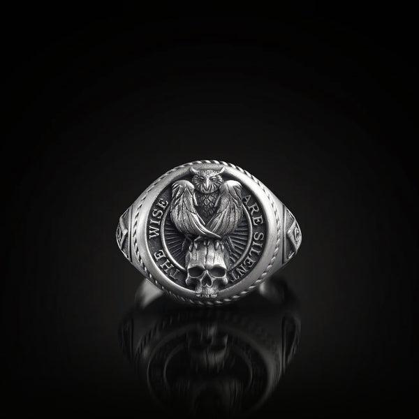 Silver signe ring with owl and skull design and engraved text on a black background