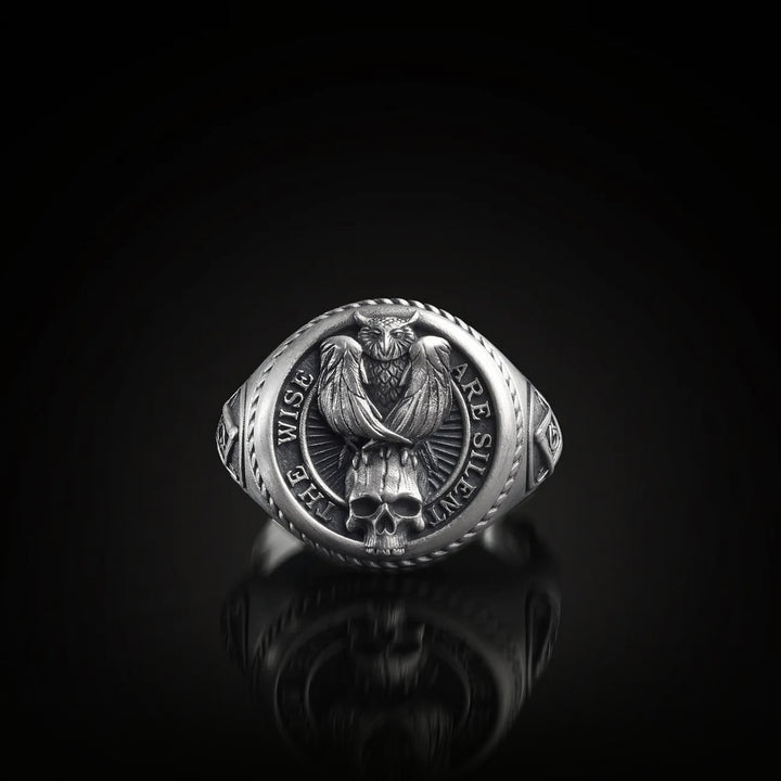 Silver signe ring with owl and skull design and engraved text on a black background