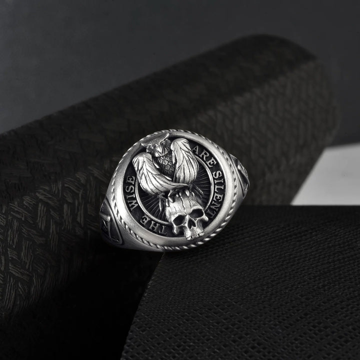 Silver ring with engraved “The Wise Are Silent” quote on a textured black surface