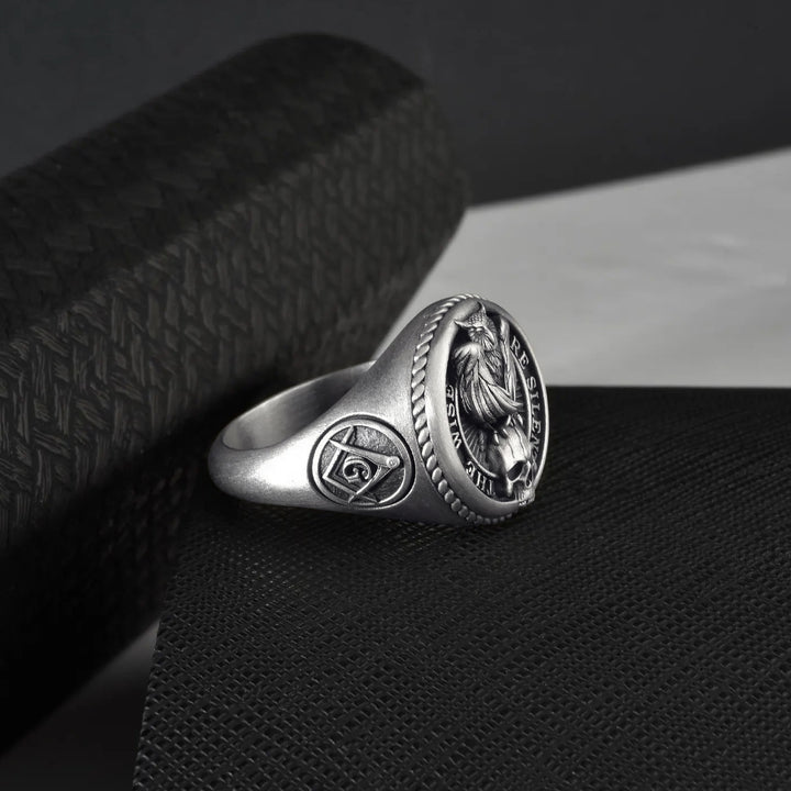 Silver ring with freemason symbol design on a dark textured surface