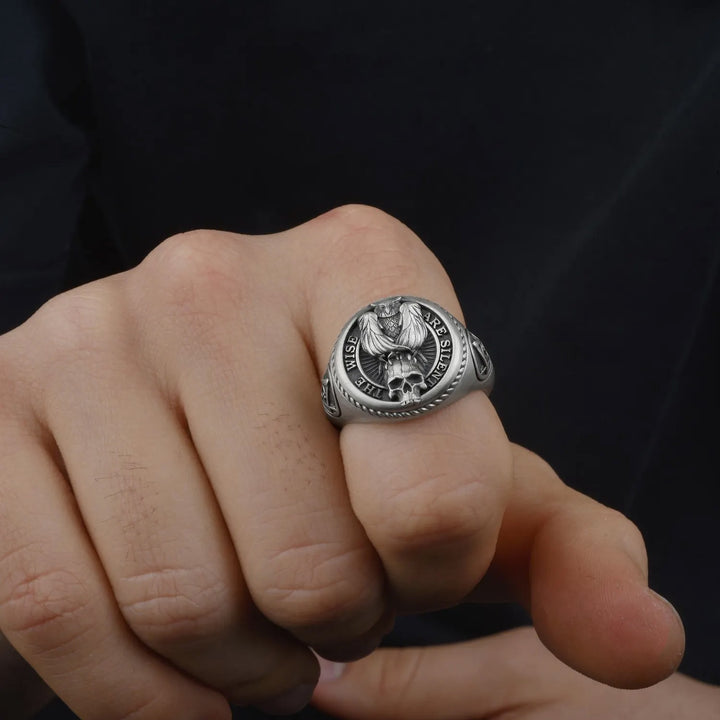 Silver ring with a detailed Owl & Skul design on a person's finger against a dark background