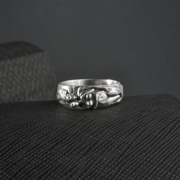 Silver spooning ring with intricate design on a textured surface