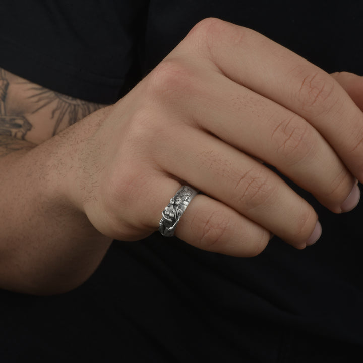 Close-up of a hand wearing a handcrafted silver couple ring with a dark background