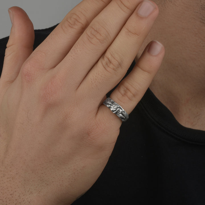 Hand wearing a matte finish silver ring with a dark background