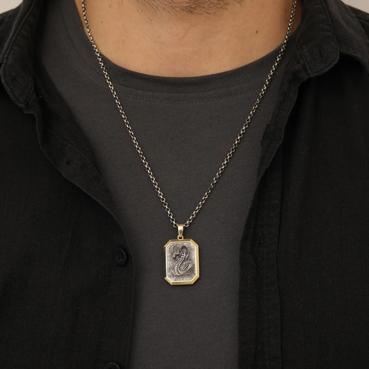 Necklace with a serpent pendant worn by a person wearing a black shirt.