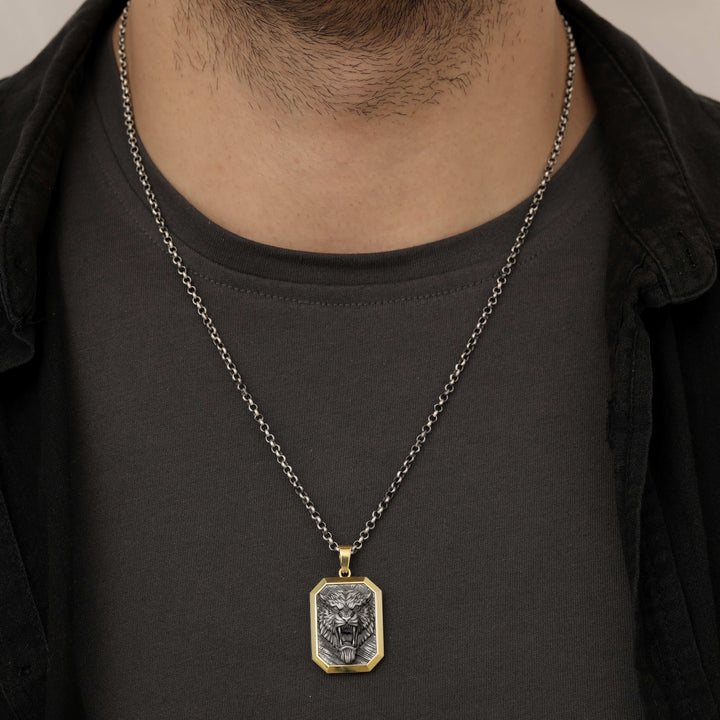 Person wearing a necklace with a roaring tiger pendant on a plain background
